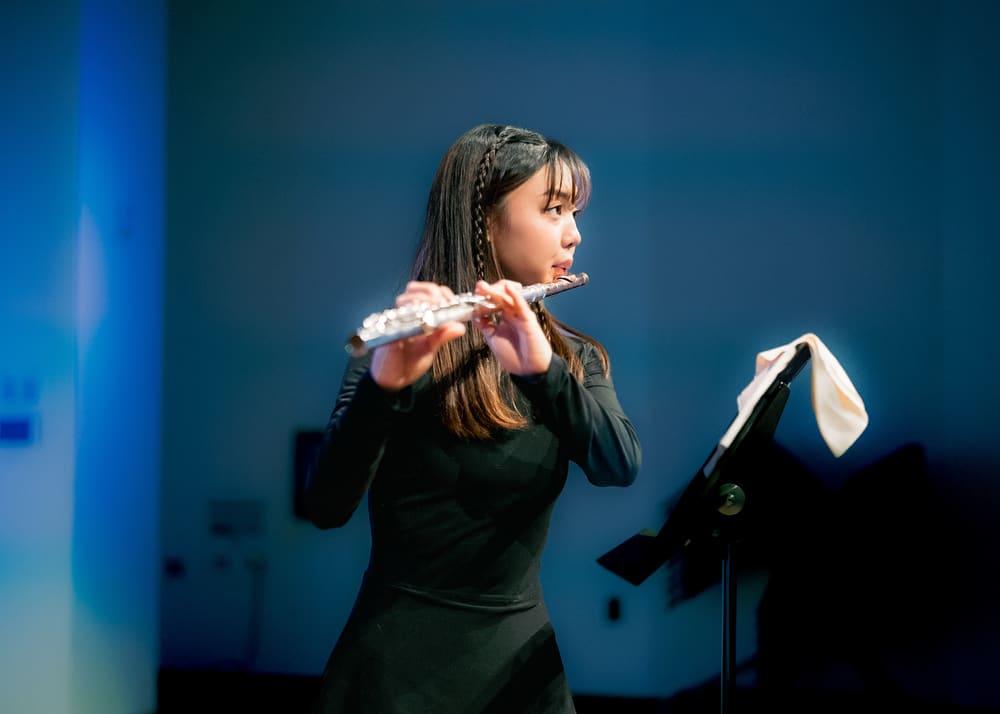 Monica playing the flute against a blue backdrop