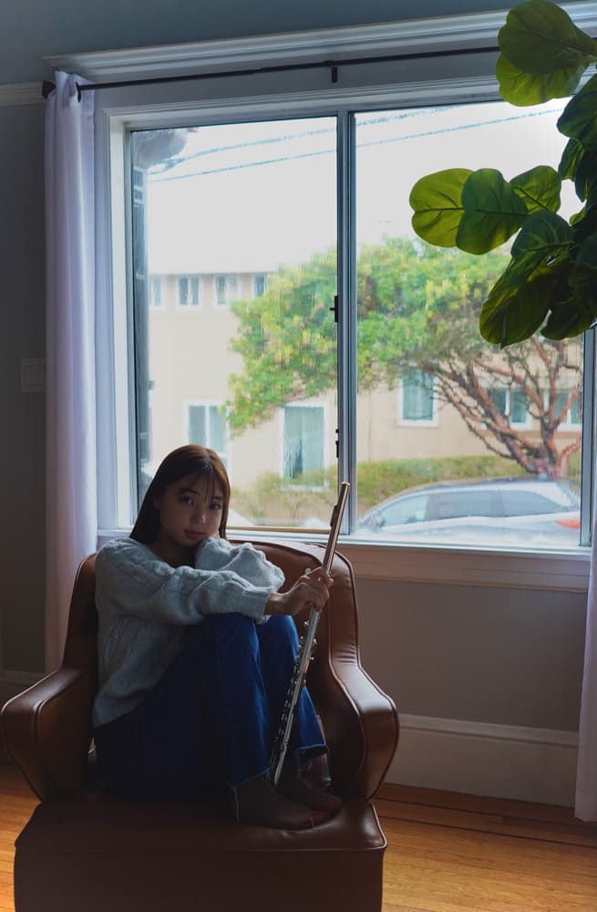Monica sitting by a window with her flute