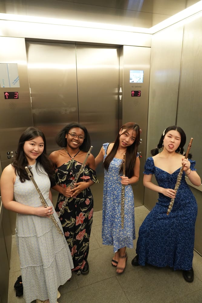 Four flutists posing together in their concert dresses