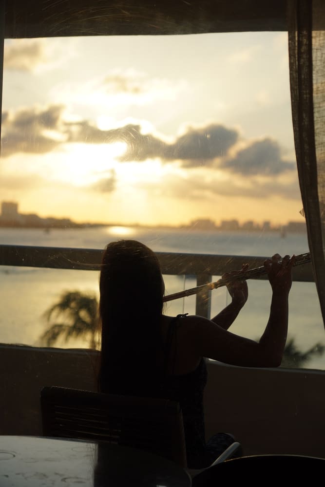 Silhouette of Monica playing the flute at sunset